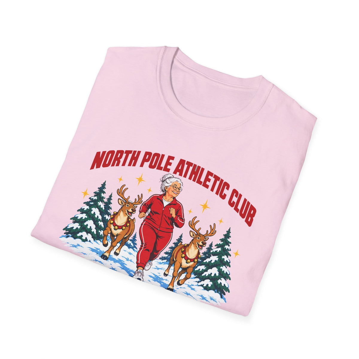 Folded light pink t-shirt printed with "NORTH POLE ATHLETIC CLUB" in red and "Winter Training Season" in green script, with a white-haired woman in a red tracksuit jogging between two reindeer through snowy pine trees