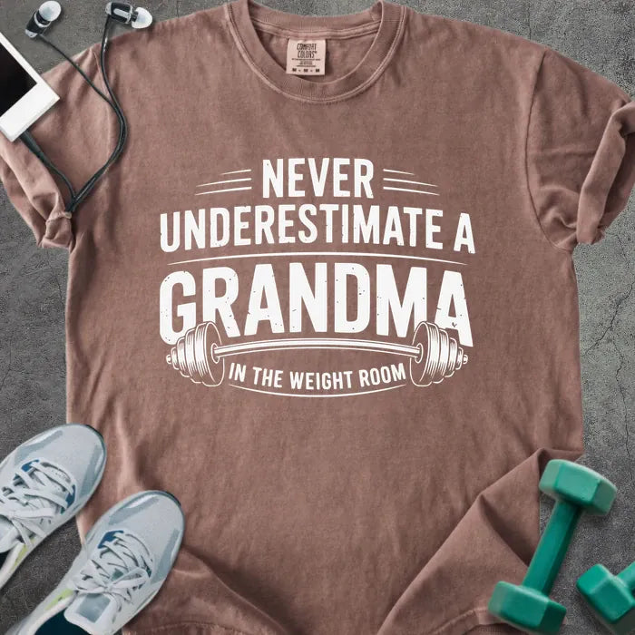 Espresso t-shirt printed with "Never Underestimate a Grandma in the Weight Room" in white, with a barbell graphic