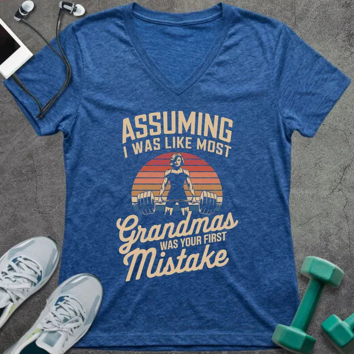 Heather true royal t-shirt printed with "ASSUMING I WAS LIKE MOST Grandmas WAS YOUR FIRST Mistake" in cream, orange, red, black, with a muscular woman silhouette deadlifting over a retro sunset