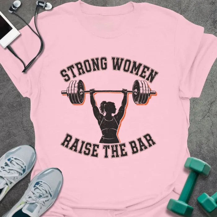 Light Pink t-shirt printed with "STRONG WOMEN RAISE THE BAR" in black lettering, with a silhouette of a woman weightlifter raising a barbell overhead