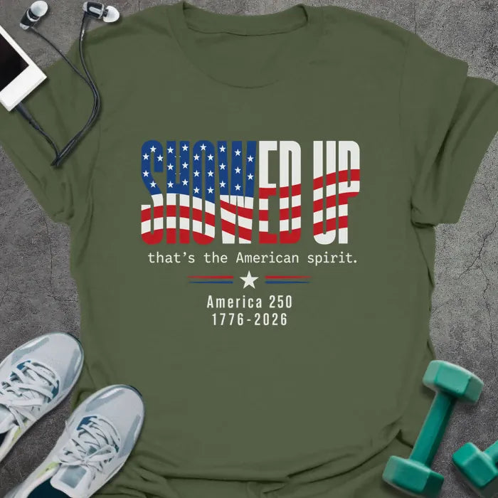 Military green t-shirt printed with "FIND UP that's the American spirit. America 250 1776-2026" in white and red, with an American flag graphic