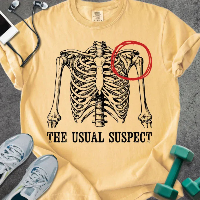 Mustard t-shirt printed with "The Usual Suspect", with skeleton ribcage and red circled heart