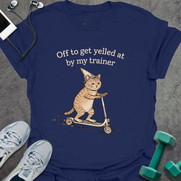 Navy t-shirt printed with "Off to get yelled at by my trainer" in tan, white, with a cat on a scooter
