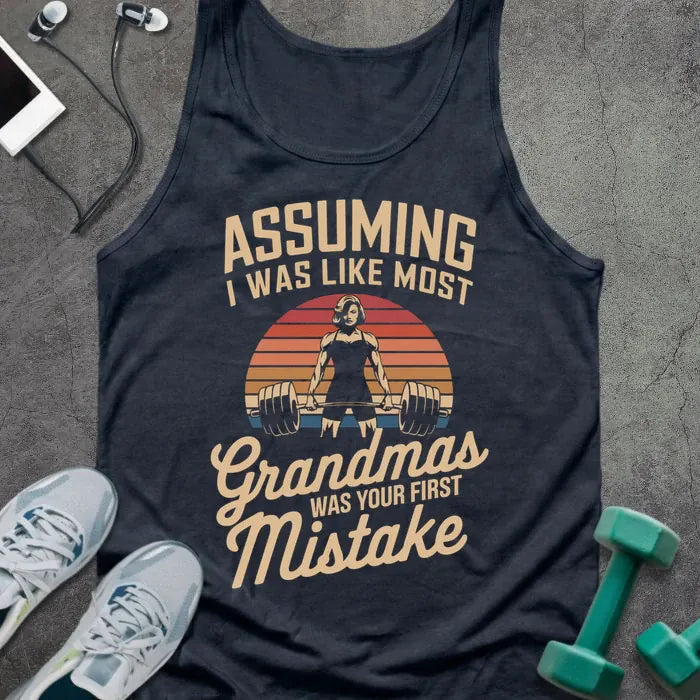 Navy tank top printed with "ASSUMING I WAS LIKE MOST Grandmas WAS YOUR FIRST MISTAKE" in tan and orange, with silhouette and sunset stripes