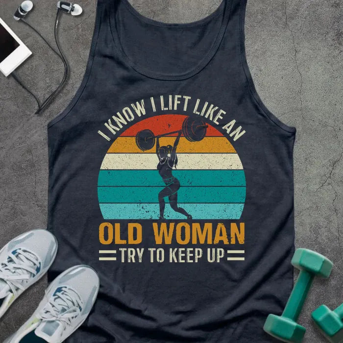 Navy tank top printed with "I Know I Lift Like an Old Woman Try to Keep Up" in white, orange, and teal, with silhouette and sunset stripes