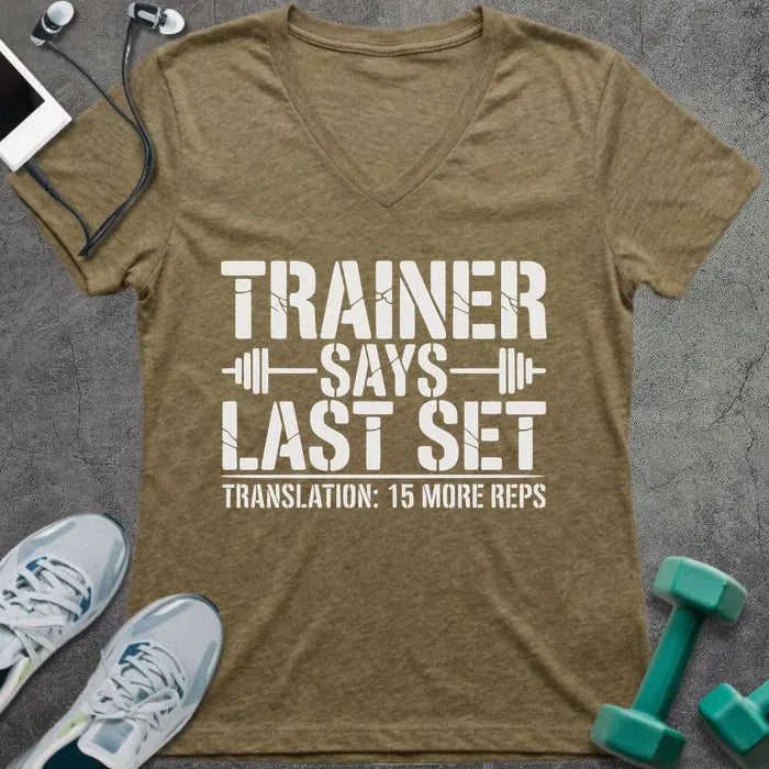 Tan v-neck reading "TRAINER SAYS LAST SET" with barbell and "TRANSLATION: 15 MORE REPS"