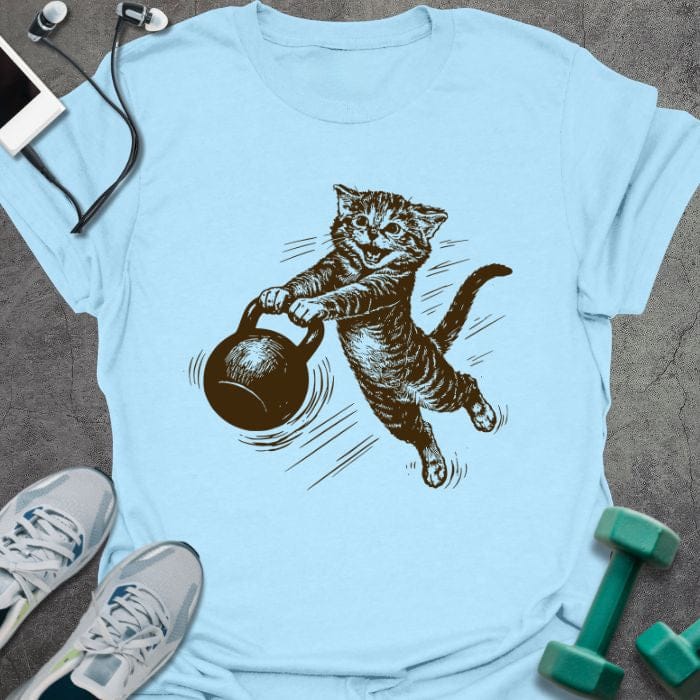 Light blue t-shirt depicting cat swinging a kettlebell in brown line art style