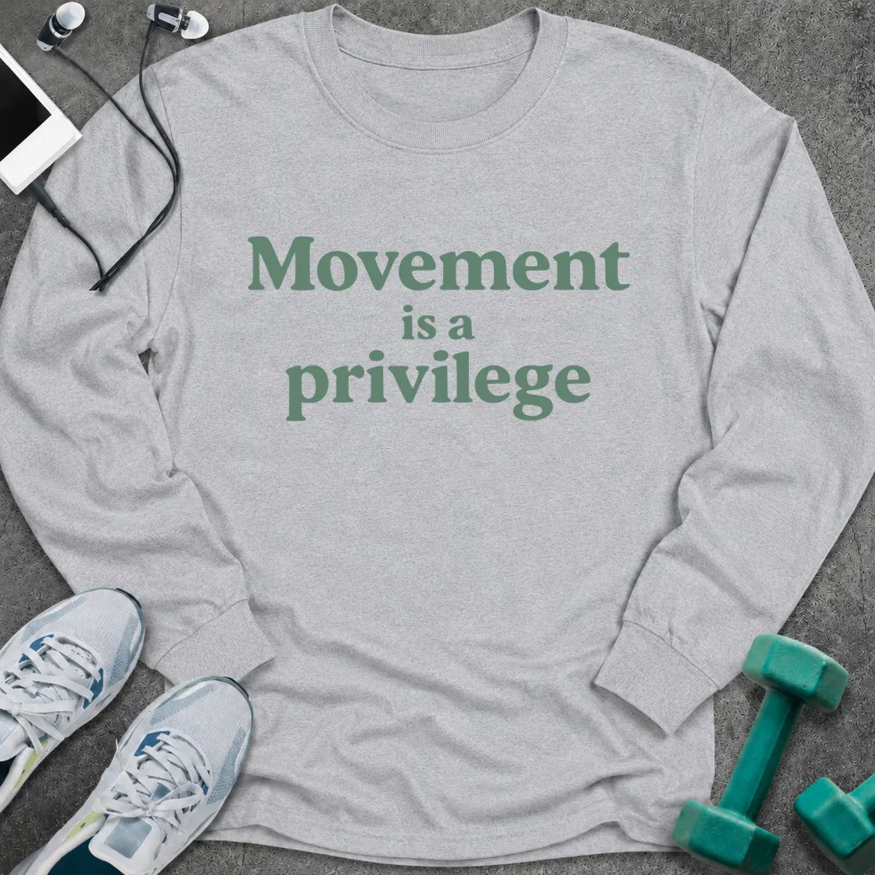 Ash long sleeve tee printed with "Movement is a privilege" in green serif lettering