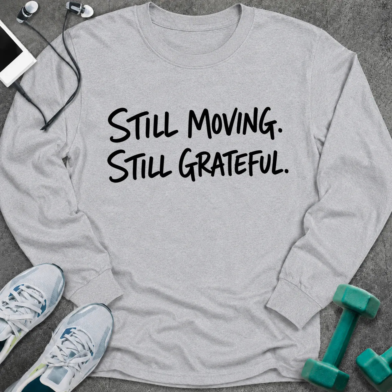 Ash long sleeve tee printed with "Still Moving. Still Grateful." in black handwritten lettering