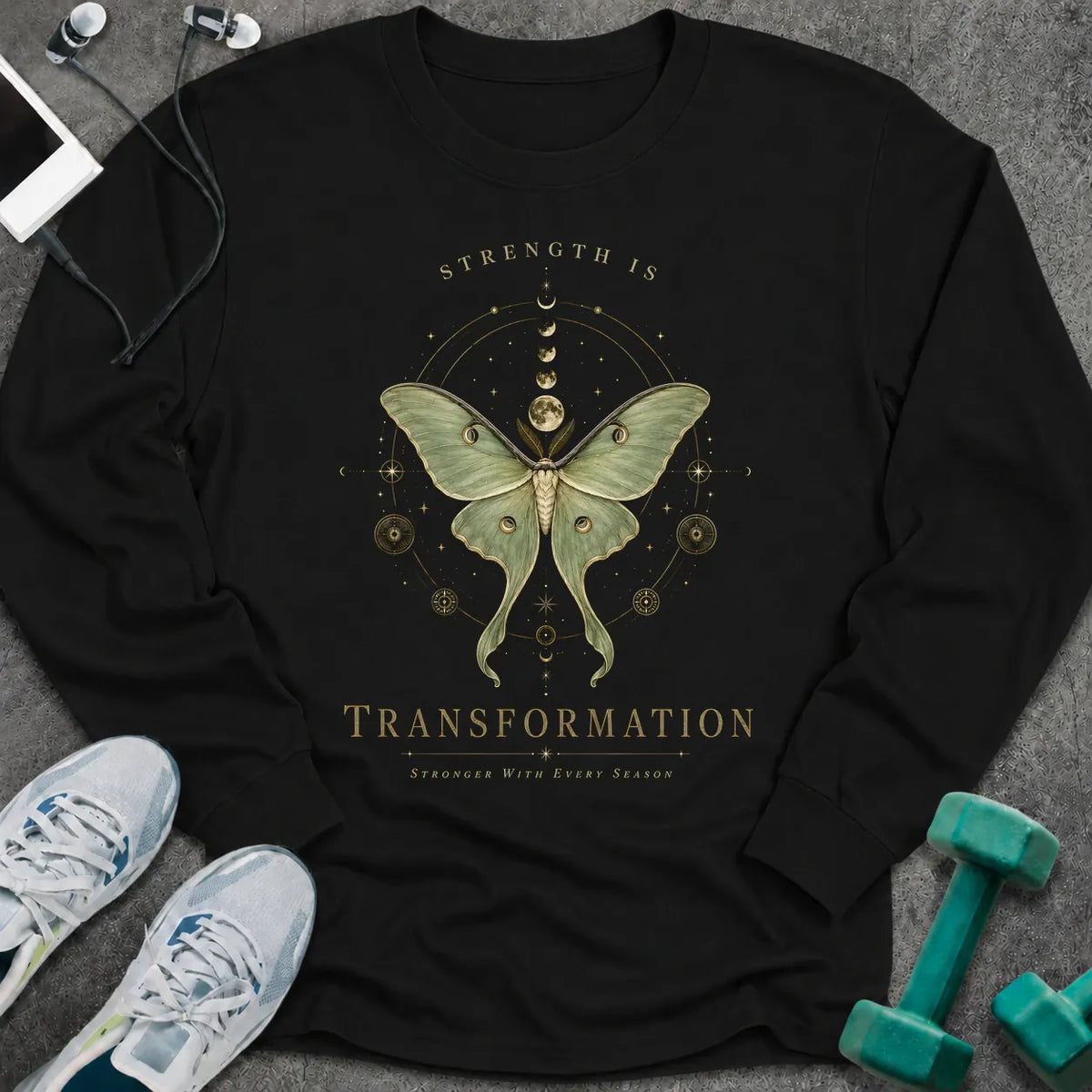 Black long sleeve tee printed with "Strength Is Transformation" in gold, with a luna moth beneath a row of moon phases