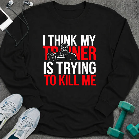 Black long sleeve tee printed with "I Think My Trainer Is Trying To Kill Me" in white and red, with a trainer figure behind the lettering