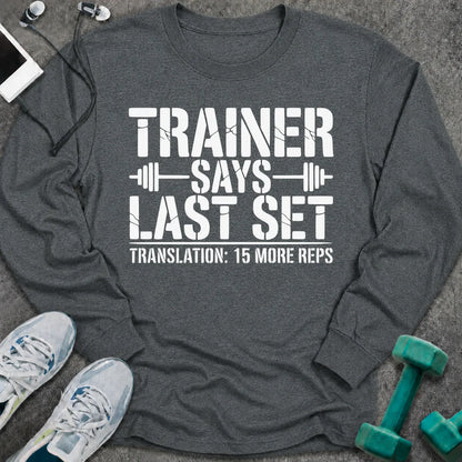 Dark heather long sleeve tee printed with "Trainer Says Last Set. Translation: 15 More Reps" in white, with barbell accents