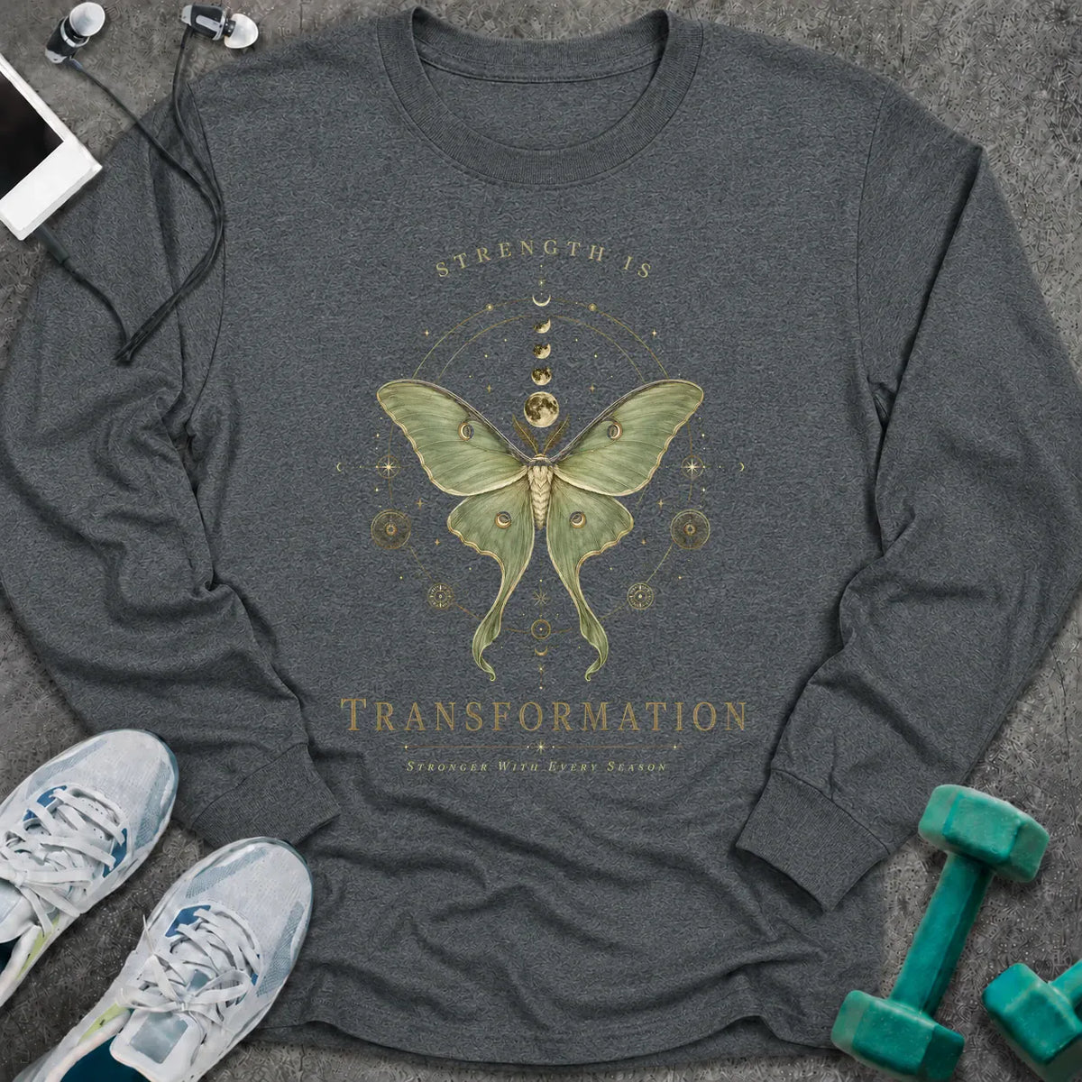 Dark heather long sleeve tee printed with "Strength Is Transformation" in gold, with a luna moth beneath a row of moon phases