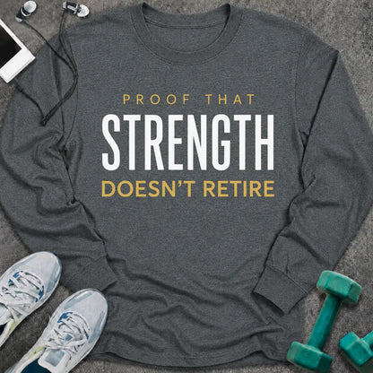 Dark heather long sleeve tee printed with "Proof That Strength Doesn't Retire" in white and gold