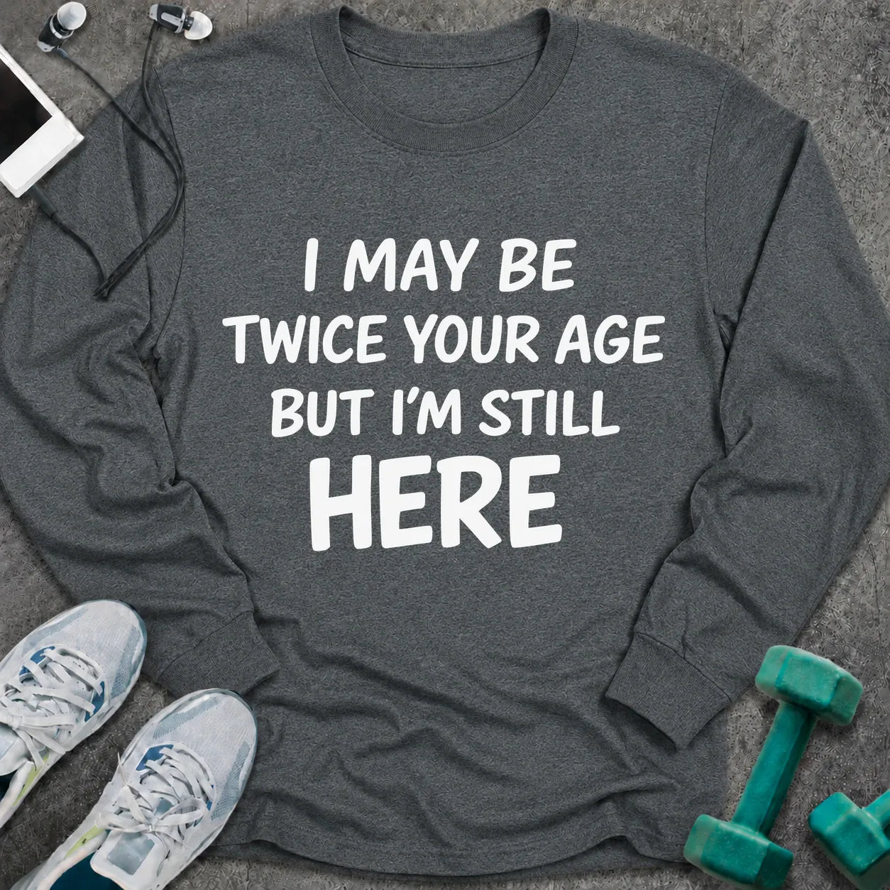 Dark heather long sleeve tee printed with "I May Be Twice Your Age But I'm Still Here" in white