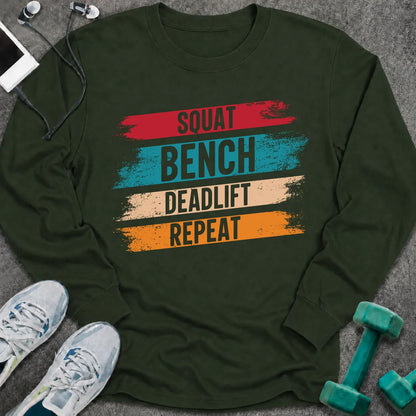 Forest green long sleeve tee printed with "Squat Bench Deadlift Repeat" in white, with teal, cream and orange brush strokes behind each word