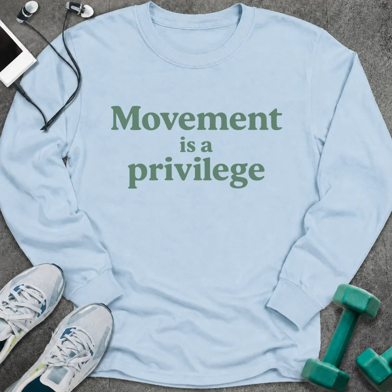 Light blue long sleeve tee printed with "Movement is a privilege" in green serif lettering