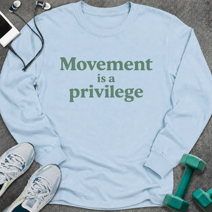 Light blue long sleeve tee printed with "Movement is a privilege" in green serif lettering