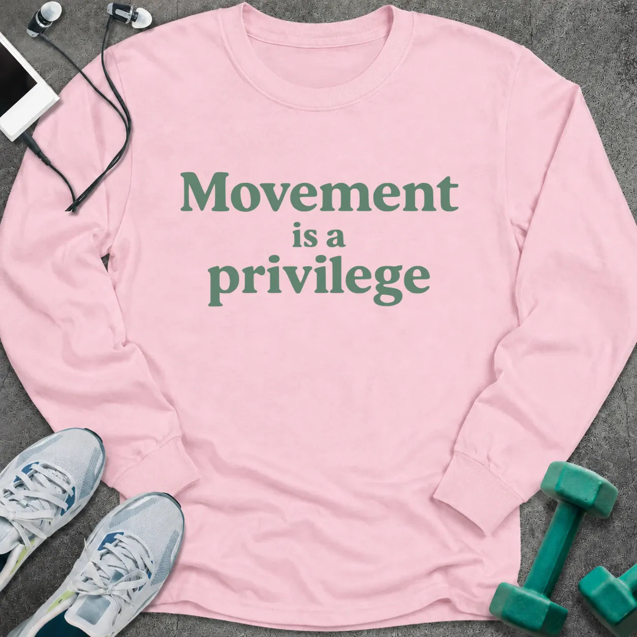 Light pink long sleeve tee printed with "Movement is a privilege" in green serif lettering