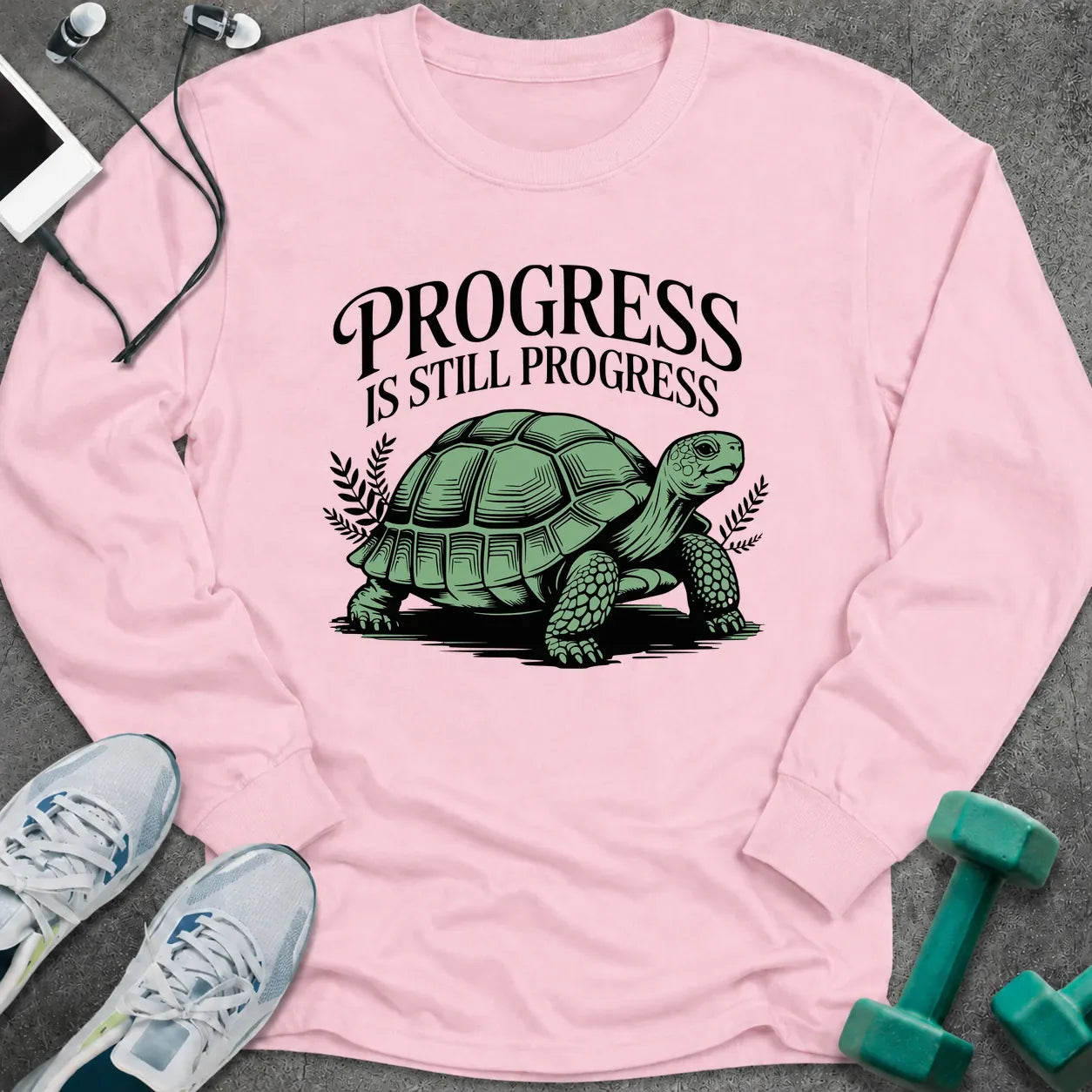 Light pink long sleeve tee printed with "Progress Is Still Progress" in black, with a tortoise
