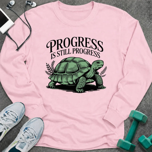 Light pink long sleeve tee printed with "Progress Is Still Progress" in black, with a tortoise