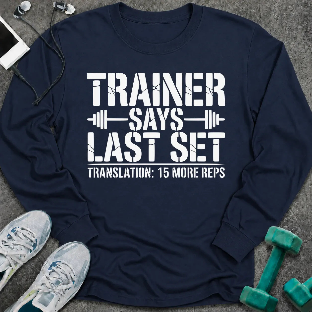 Navy long sleeve tee printed with "Trainer Says Last Set. Translation: 15 More Reps" in white, with barbell accents