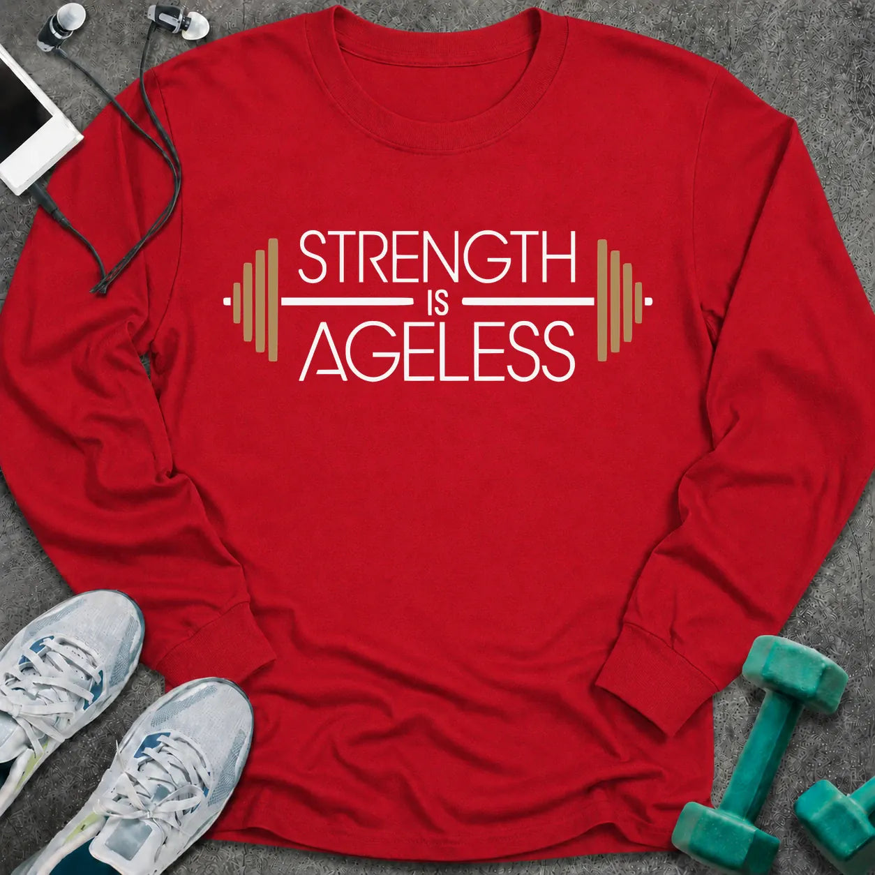 Red long sleeve tee printed with "Strength is Ageless" in white and gold, with a barbell framing the words