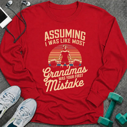 Red long sleeve tee printed with "Assuming I Was Like Most Grandmas Was Your First Mistake" in cream and gold, with a woman deadlifting inside a retro sunburst