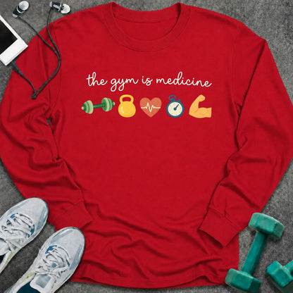 Red long sleeve tee printed with "the gym is medicine" in white script, with dumbbell, kettlebell, heart, stopwatch and flexed arm icons