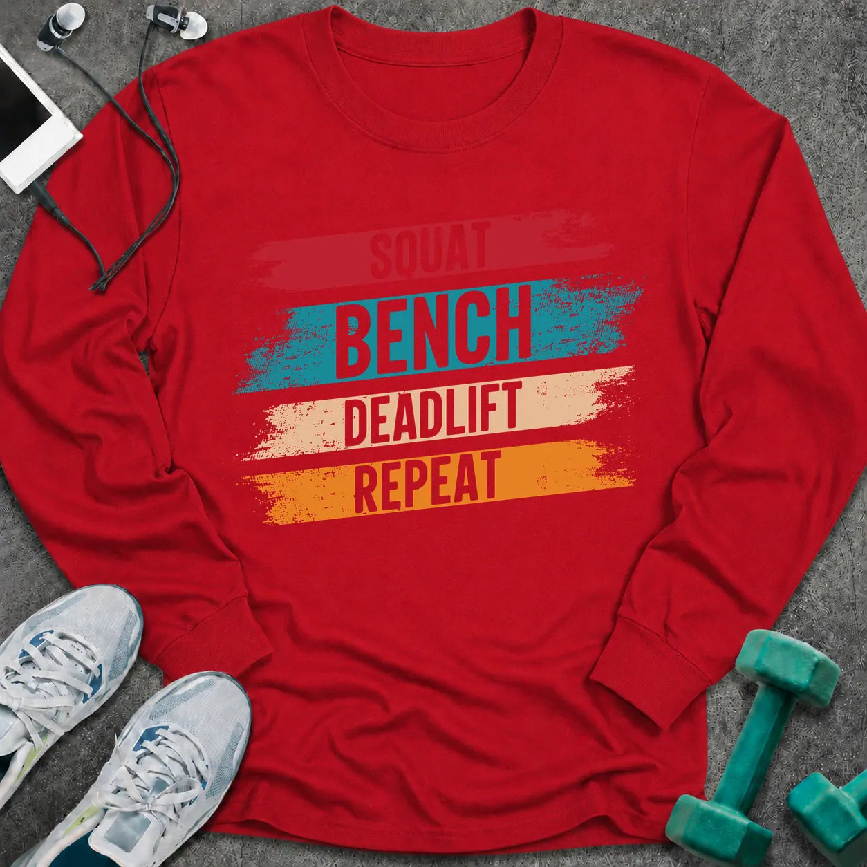 Red long sleeve tee printed with "Squat Bench Deadlift Repeat" in white, with teal, cream and orange brush strokes behind each word