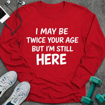 Red long sleeve tee printed with "I May Be Twice Your Age But I'm Still Here" in white
