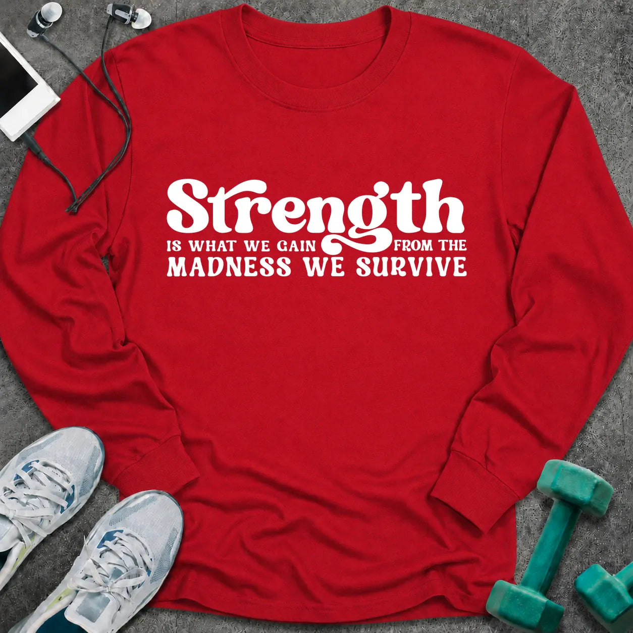 Red long sleeve tee printed with "Strength Is What We Gain From The Madness We Survive" in white