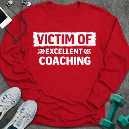 Red long sleeve tee printed with "Victim Of Excellent Coaching" in white, with a painted brush stroke banner