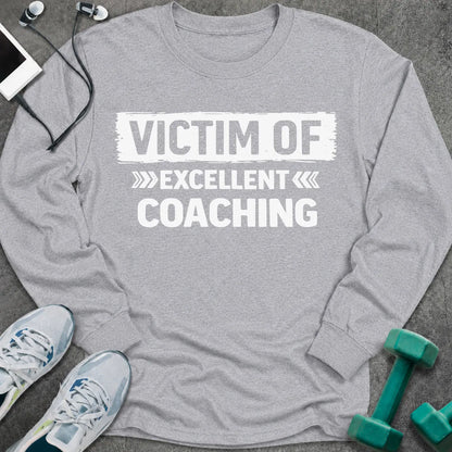 Sport grey long sleeve tee printed with "Victim Of Excellent Coaching" in white, with a painted brush stroke banner
