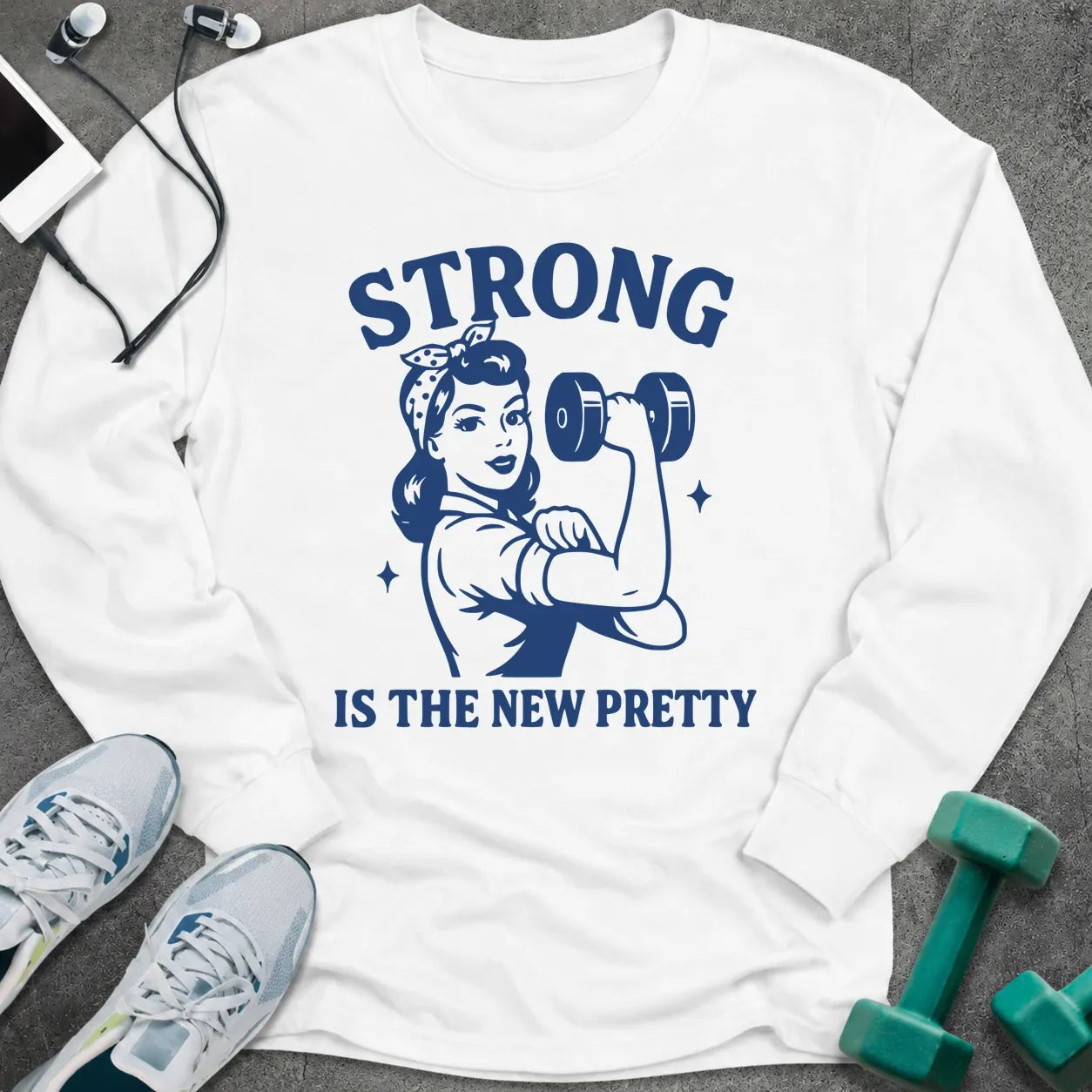 White long sleeve tee printed with "Strong Is The New Pretty" in navy, with a retro woman flexing with a dumbbell