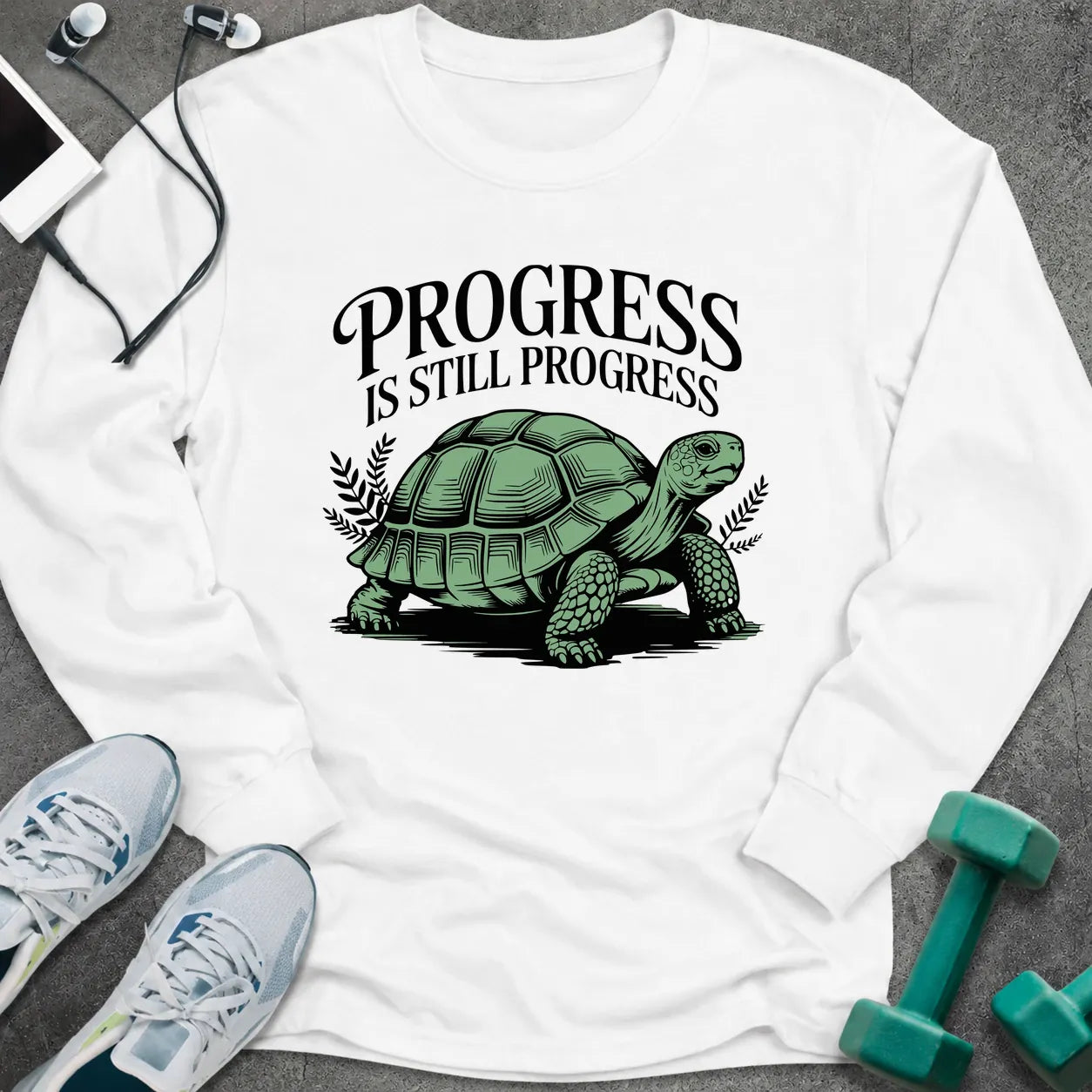 White long sleeve tee printed with "Progress Is Still Progress" in black, with a tortoise