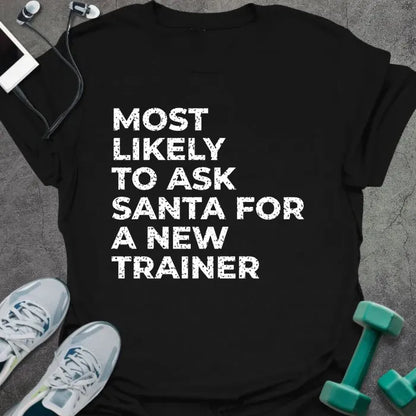 Black t-shirt printed with "MOST LIKELY TO ASK SANTA FOR A NEW TRAINER" in white
