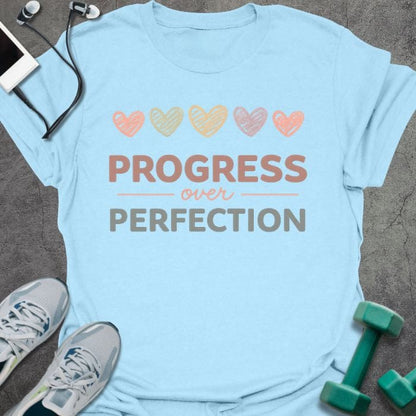 Light blue t-shirt with colored hearts and "PROGRESS over PERFECTION" text