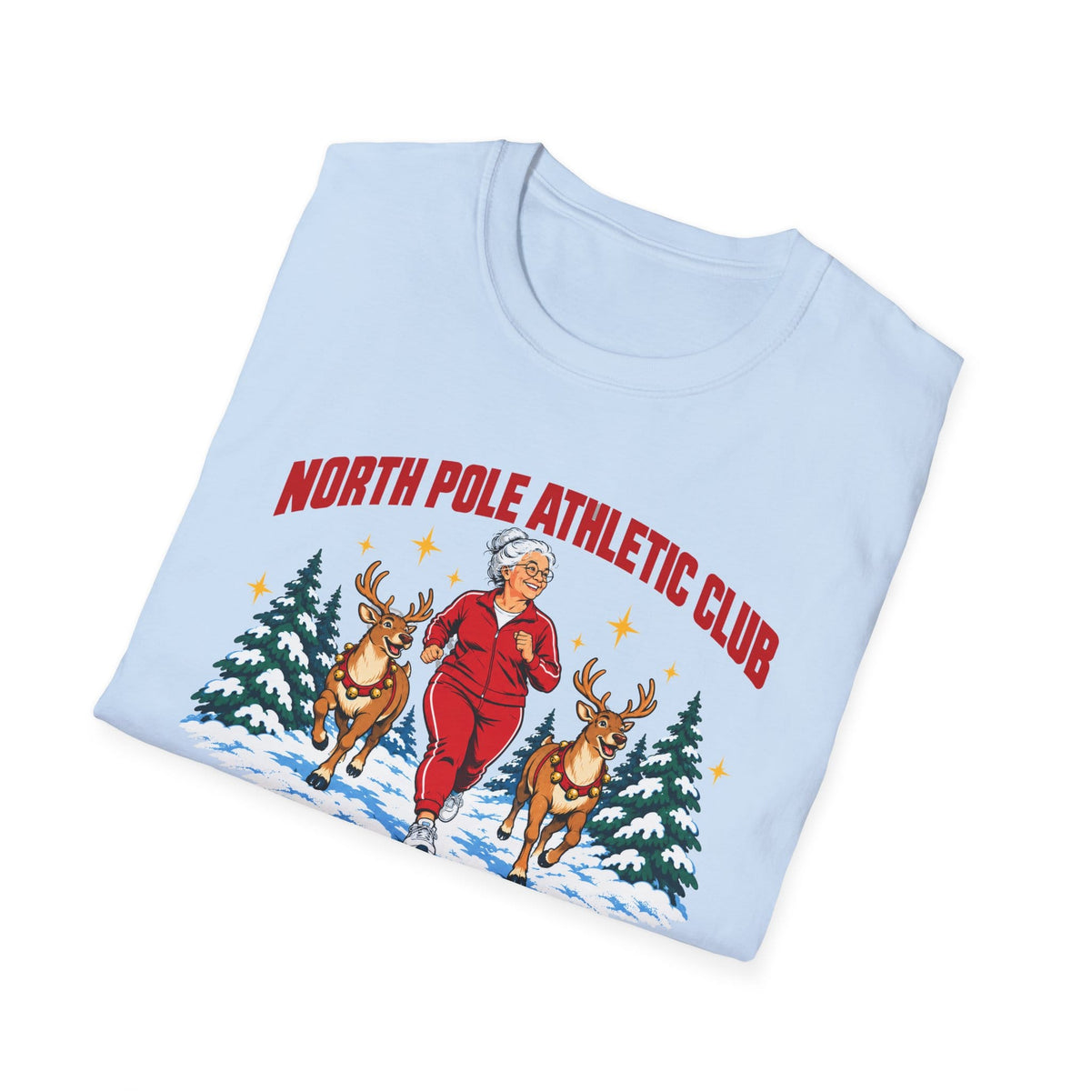 Folded light blue t-shirt printed with "NORTH POLE ATHLETIC CLUB" in red and "Winter Training Season" in green script, with a white-haired woman in a red tracksuit jogging between two reindeer through snowy pine trees