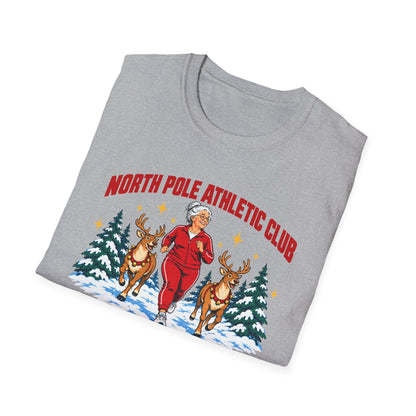Folded sport grey t-shirt printed with "NORTH POLE ATHLETIC CLUB" in red and "Winter Training Season" in green script, with a white-haired woman in a red tracksuit jogging between two reindeer through snowy pine trees
