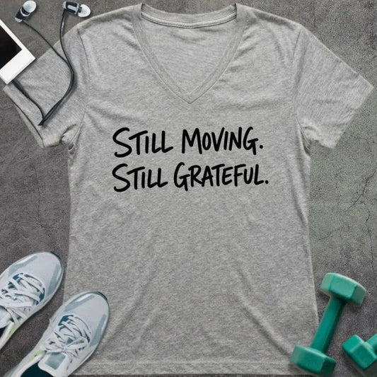 Athletic heather v-neck tee printed with "STILL MOVING. STILL GRATEFUL." in black