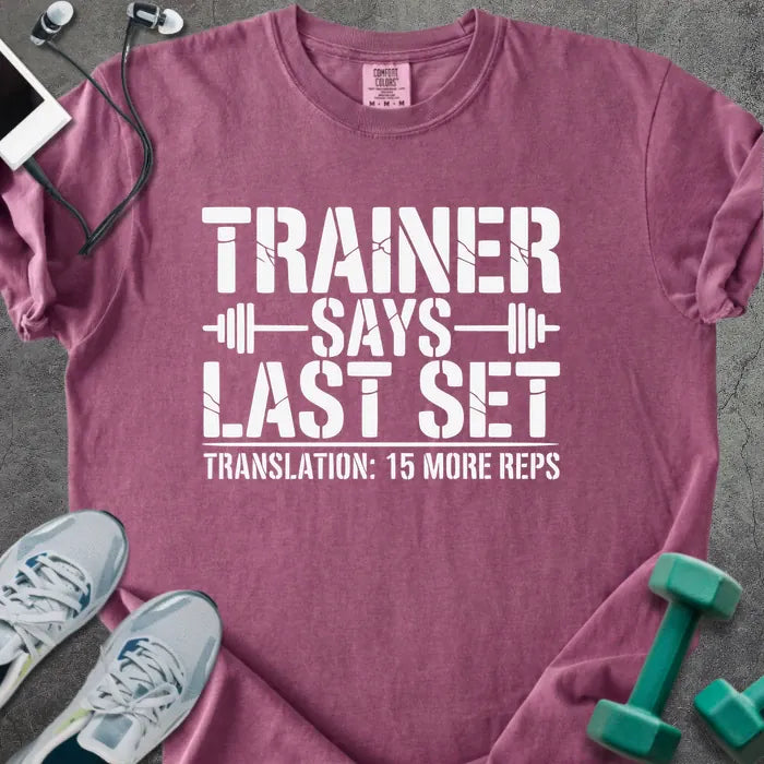 Berry t-shirt printed with "Trainer Says Last Set Translation: 15 More Reps" in white, with a barbell graphic
