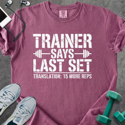 Berry t-shirt printed with "Trainer Says Last Set Translation: 15 More Reps" in white, with a barbell graphic