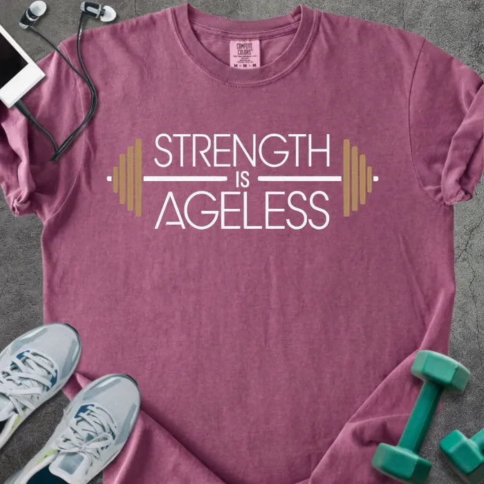 Berry t-shirt printed with "Strength is Ageless" in white and gold, with a barbell graphic