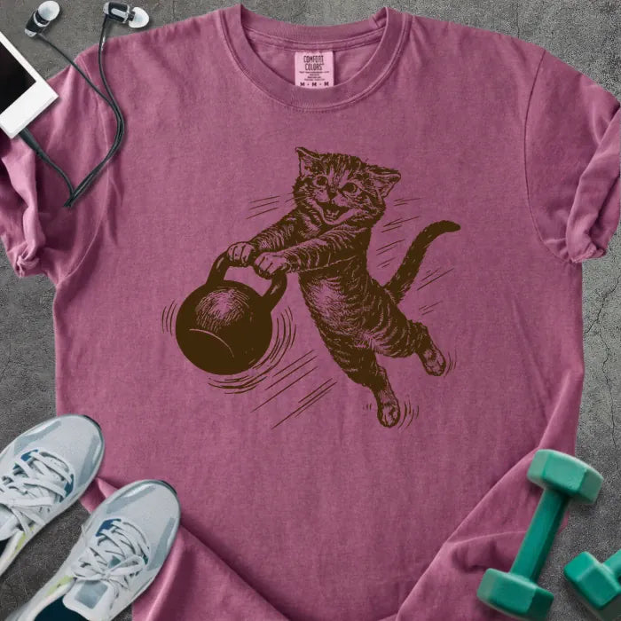 Berry t-shirt with an illustration of a cat swinging a kettlebell in brown and white