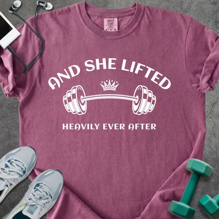 Berry t-shirt printed with "And She Lifted Heavily Ever After" in white, with a barbell and crown