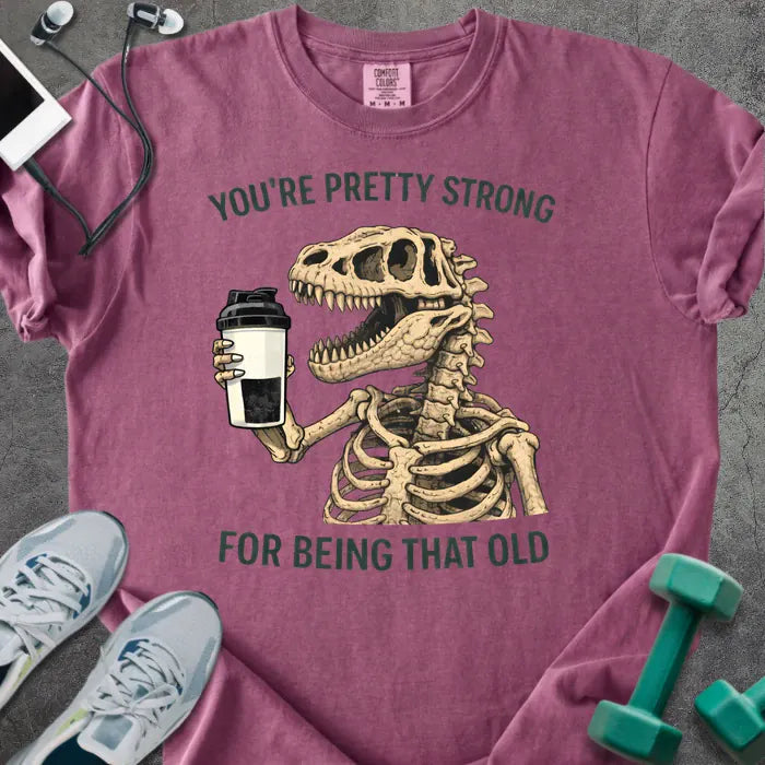 Berry t-shirt printed with "You're Pretty Strong for Being That Old" in green, with skeleton holding a coffee cup