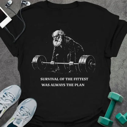Black t-shirt printed with "Survival of the Fittest Was Always the Plan" in white, with bearded figure lifting barbell graphic