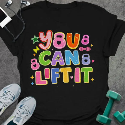 Black t-shirt printed with "You Can Lift it" in pink, orange, green, purple, blue, yellow, with bubble letters, stars, sparkles, and small dumbbell doodles