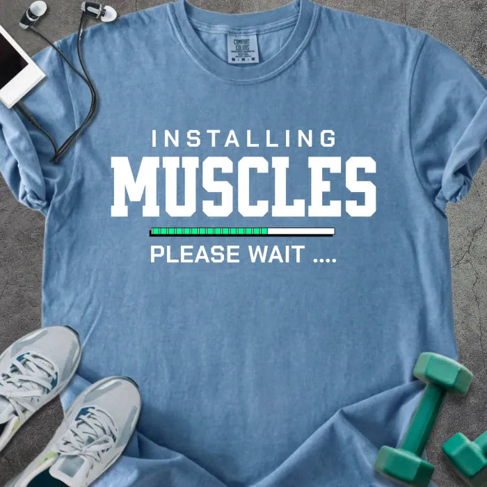 Blue jean t-shirt printed with "Installing Muscles Please Wait ...." in white and multicolor, with a loading bar